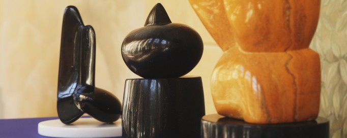 Kilka abstrakcyjnych rzeźb stojących obok siebie w rzędzie na niebieskim cokole.