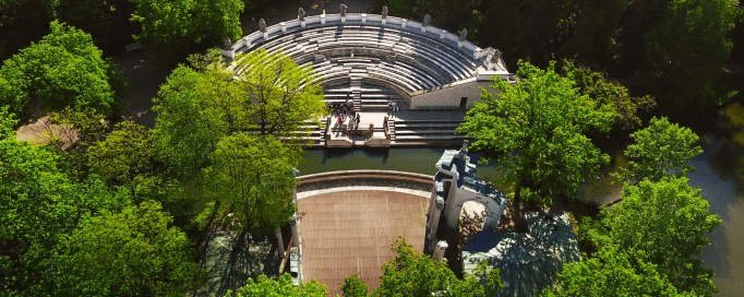 Widok z lotu ptaka na Amfiteatr otoczony zielenią i wodą.