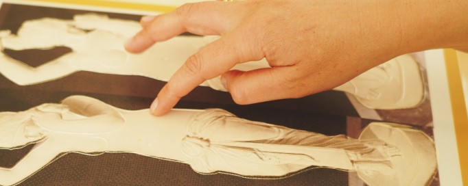 Ręce dotykające płaskorzeźb przedstawiających kobiece postaci. 