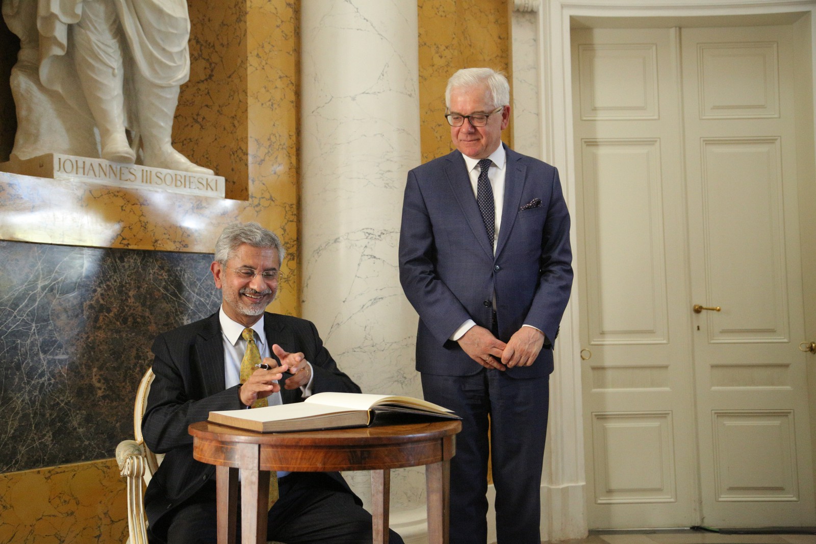 Minister Subrahmanyam Jaishankar wpisuje się w Pałacu na Wyspie do księgi pamiątkowej Muzeum. Po prawej stronie stoi minister Czaputowicz.