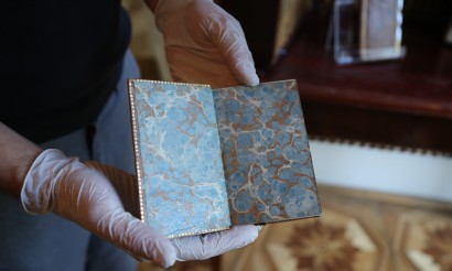 Widoczne dłonie archiwisty w rękawiczkach ochronnych pokazujące zabytkową książkę