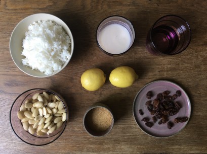 Sześć misek, w których znajdują się woda, mleko, ryż, migdały, rodzynki i cukier, pośrodku leżą dwie cytryny.