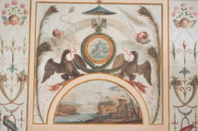 Grafika przedstawiająca dwa ptaki trzymające w dziobach wieniec laurowy, okalający medalion z przedstawieniem kobiety, po bokach znajdują się pawie pióra, amorki oraz ptaki, poniżej widać pejzaż z krajobrazem nad rzeką.