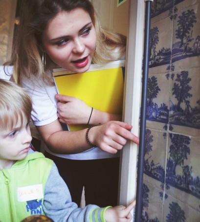 Młoda kobieta wskazuje ręką małemu dziecku niebieskie malunki na ścianie. 