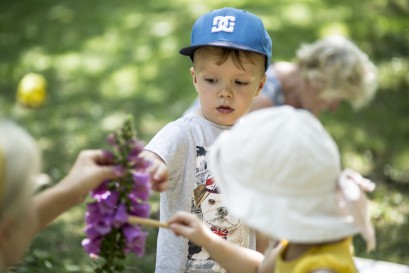 Grupa dzieci stojąca przy fioletowym kwiecie.