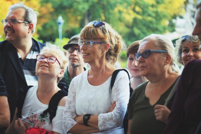 Grupa starszych kobiet i mężczyzn stojąca w łazienkowskich ogrodach. 