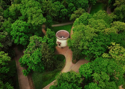 Widok z lotu ptaka na budynek Wodozbioru z okrągłym dachem. Wodozbiór znajduje się wśród drzew. 