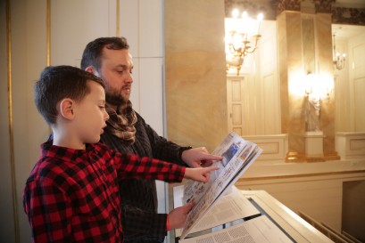 Mężczyzna z chłopcem oglądają ilustrowaną książkę. 