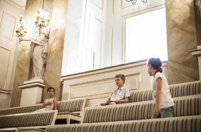 Troje dzieci na widowni Teatru Królewskiego w Starej Oranżerii. 