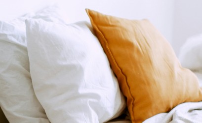 Dwie białe i jedna jasnobrązowa poduszka leżą obok siebie. 