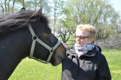 Starsza kobieta stojąca przy koniu.