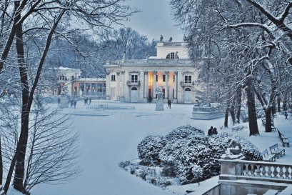 Pałac na Wyspie w zimowym otoczeniu. Budynek Pałacu i pobliskie drzewa pokrywa śnieg.