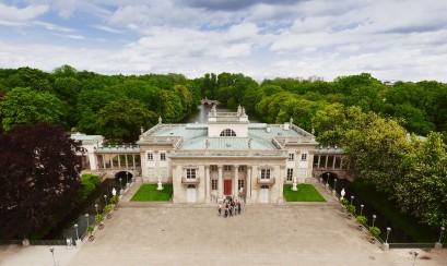 Widok na Pałac na Wyspie w otoczeniu drzew i wody. 