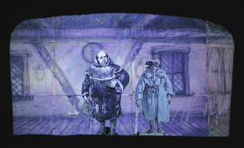 Kadr z spektaklu "Barani Kożuszek". Widać lalki z papieru, przedstawiające dwóch mężczyzn na tle ściny domu. 