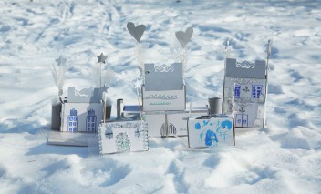 Papierowe domki stojące na śniegu.