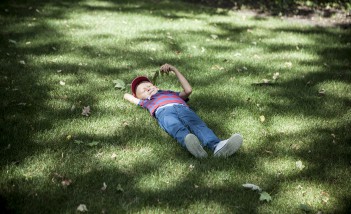 Chłopiec leżący na trawie. 