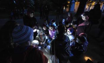 Grupa dzieci stojąca nocą przed budynkiem w Łazienkach Królewskich.