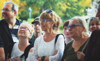 Grupa starszych kobiet i mężczyzn stojąca w łazienkowskich ogrodach. 