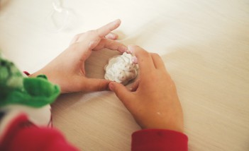 Dziecięce dłonie trzymające białą kulistą masę. 