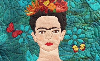 Obrazek przedstawiający kobietę w czarnej bluzce, z naszyjnikiem na szyi i wiankiem z kwiatów na głowie.
