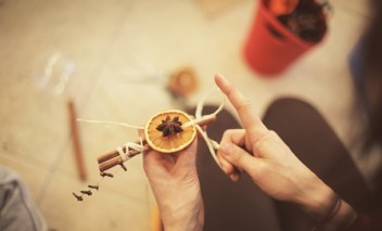 Kobieca ręka trzymająca laskę cynamonu z plastrem pomarańczy.