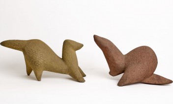 Dwie gliniane, brązowe figurki w kształcie zwierząt.