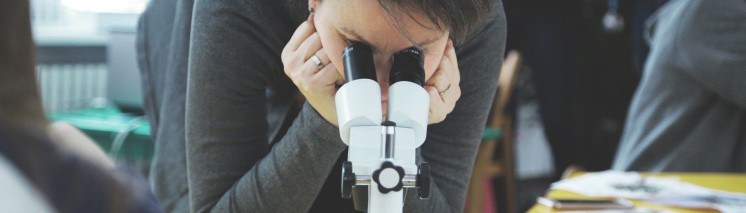 Osoba patrząca przez mikroskop.