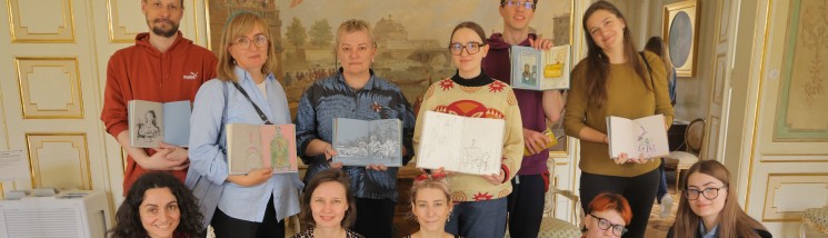 Grupa kilkunastu osób pozuje do zdjęcia, trzymając przed sobą książki.