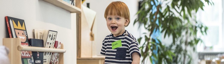 Mały chłopiec bawi się w pokoju z zabawkami na małej zjeżdżalni. 